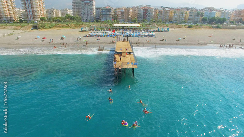 Many people swim in sea near pier on city beach at summer sunny day. Aerial view videoframe