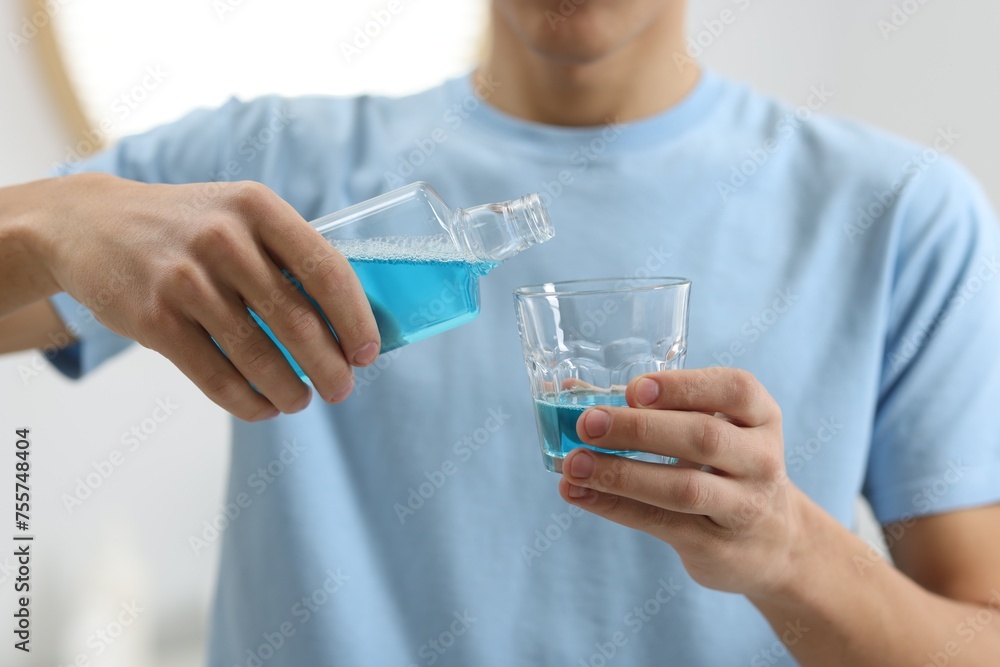 Young man using mouthwash indoors, closeup view Young man using mouthwash indoors, closeup view