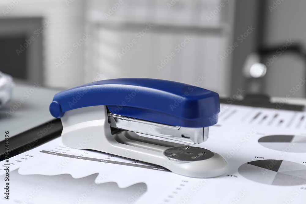 Stapler and document on table indoors, closeup Stapler and document on table indoors, closeup