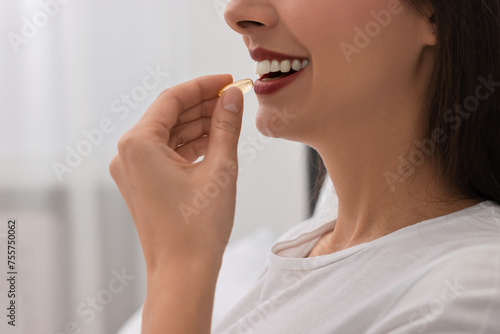 Woman taking vitamin pill at home  closeup