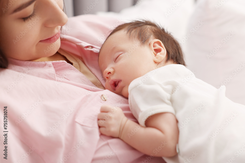 Mother with her sleeping newborn baby on bed, closeup Mother with her sleeping newborn baby on bed, closeup