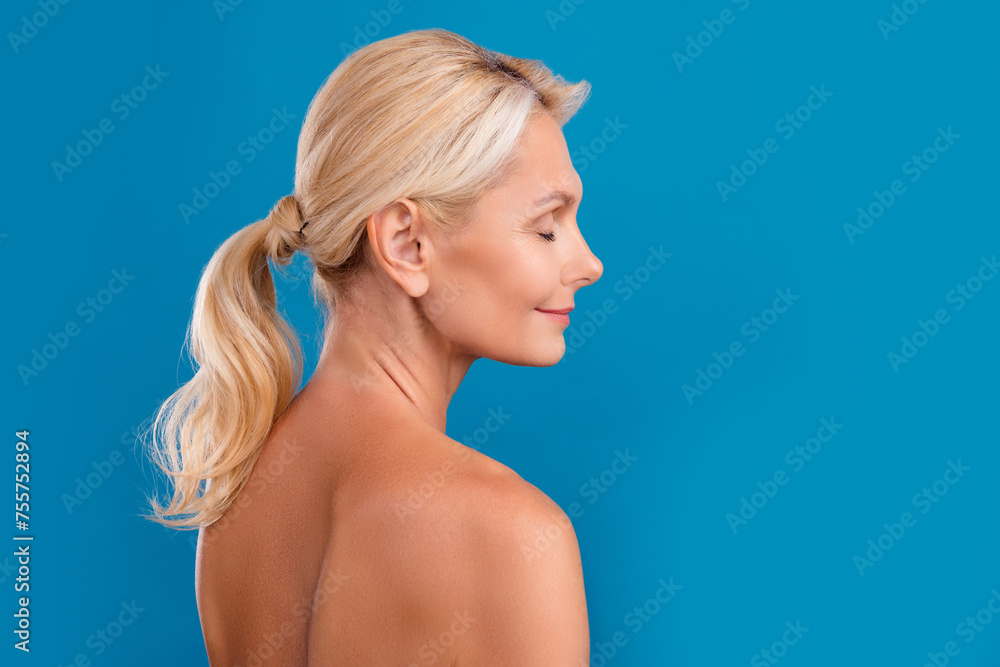 Photo of shiny dreamy senior woman nude shoulders closed eyes empty space isolated blue color background Photo of shiny dreamy senior woman nude shoulders closed eyes empty space isolated blue color background