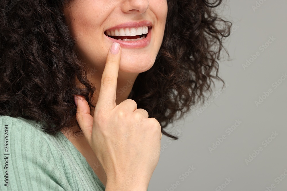 Young woman showing her teeth with whitening strip on grey background, closeup. Space for text - obrazy, fototapety, plakaty 