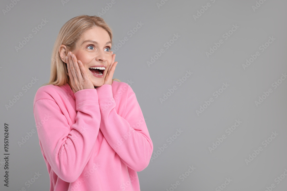 Portrait of happy surprised woman on grey background, space for text Portrait of happy surprised woman on grey background, space for text
