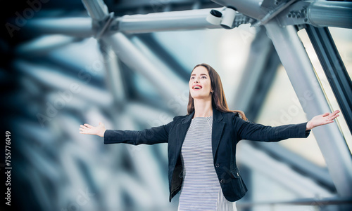 A beautiful businessman woman spreading her arms as a symbol of freedom against the background of a modern office building