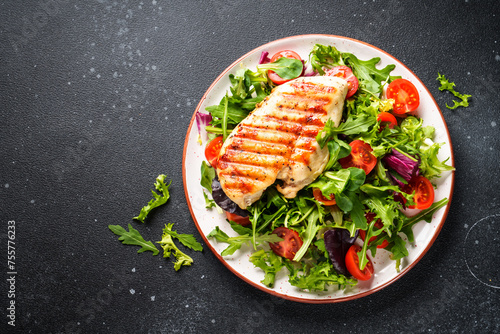 Green salad with chicken and fresh vegetables on black background. Keto diet, healthy food. © nadianb