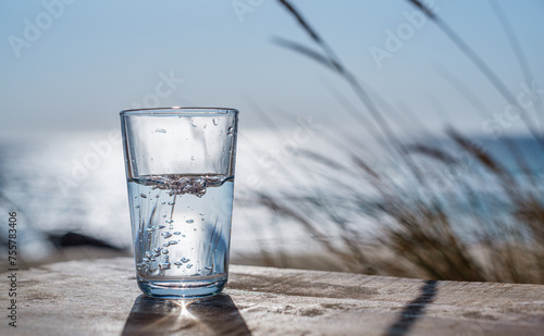 Pouring water into a glass from plastic bottle. Nature background.