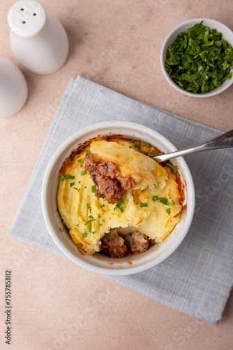 Shepherd's pie in a portioned white baking dish. Homemade traditional casserole (gratin) with minced meat and mashed potatoes. Selective focus, close-up.