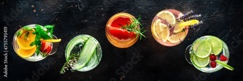 Fancy cocktails with fresh fruit panorama. Gin and tonic drinks with ice at a party, on a black background, panoramic banner, overhead flat lay shot