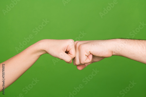 Photo of two female male arms touching fists fighting showing confrontation isolated green color background photo
