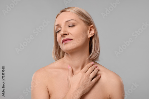 Beautiful woman touching her neck on grey background