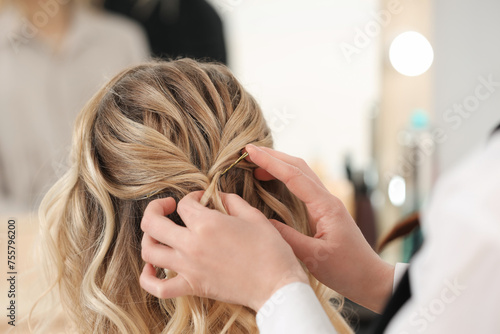 Hair styling. Professional hairdresser working with client in salon, closeup