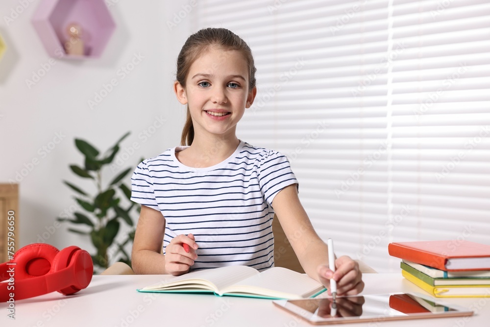 E-learning. Cute girl using tablet for studying online at table indoors E-learning. Cute girl using tablet for studying online at table indoors