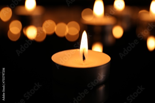 Burning candle on dark surface. Memory day