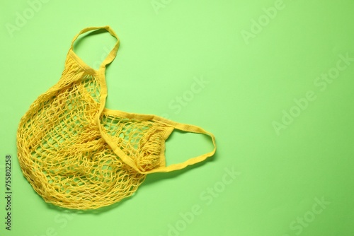 Yellow net bag on green background, top view. Space for text