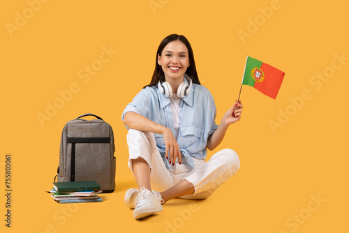 Smiling lady student with headphones and Portuguese flag, ready for cultural study session