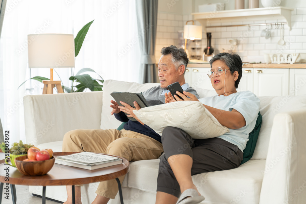 Senior Asian couple grandparents using a smart phone together on sofa at home,asian mature and retired man and woman using technology.old retired age asian indoor,at home concept Senior Asian couple grandparents using a smart phone together on sofa at home,asian mature and retired man and woman using technology.old retired age asian indoor,at home concept