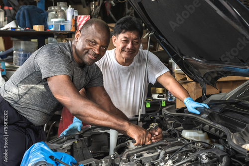 Diversity teamwork black auto mechanic with expertise Asian technician changing engine in auto repair garage