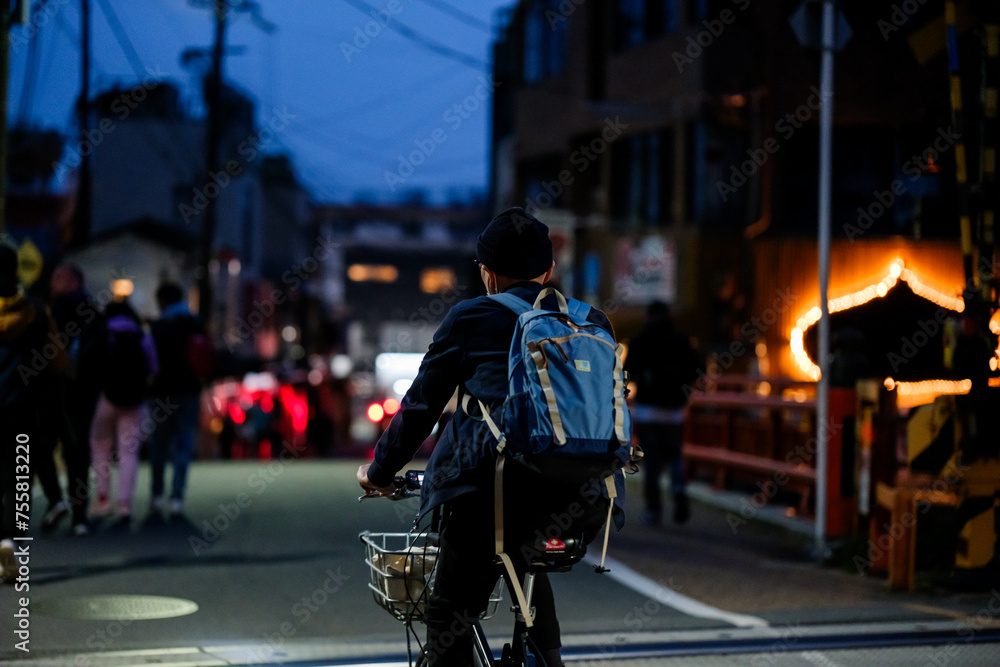 Uomo giapponese di spalle che va in bicicletta di sera in città 