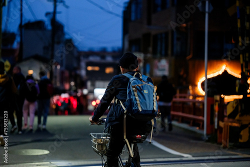 Uomo giapponese di spalle che va in bicicletta di sera in città  © Ricky Delli Paoli