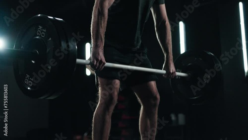 Close up shot - Unrecognisable man doing a deadlift, weight training in the gym with a dark background and mood lightening
