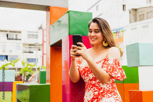 Young woman typing on cell phone in colorful environment