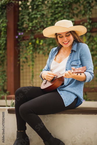 Young woman with hat playing ukulele