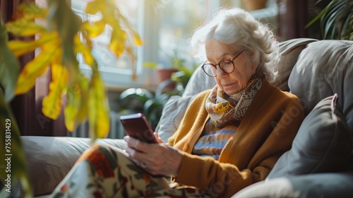 Elderly woman using smartphone on sofa in living room. photo