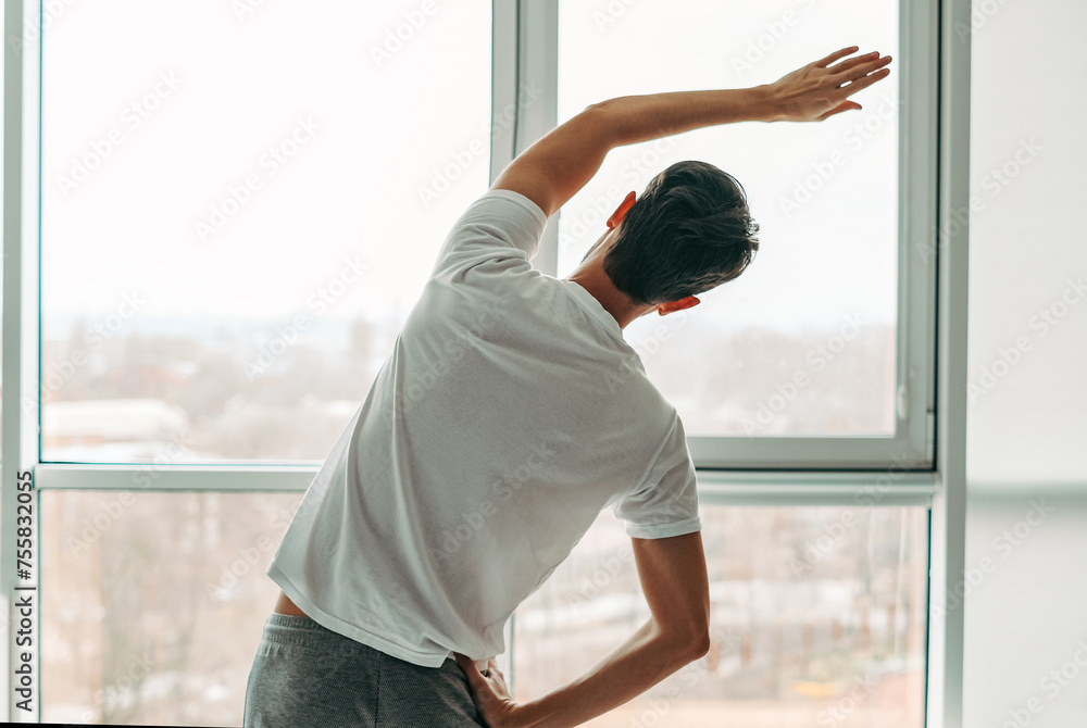 young man doing exercises at home on self-isolation view from the back