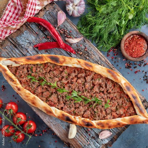 Top view of Turkish pide with minced meat, 
green peppers  on wooden tray. with ingredients around  Turkish name; Kiymali Pide. Traditional Turkish cuisine. Turkish pizza Pita with meat