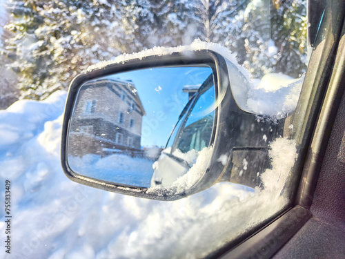 Winter Scene Featuring a Snow-Covered Car Side Mirror Reflecting Trees