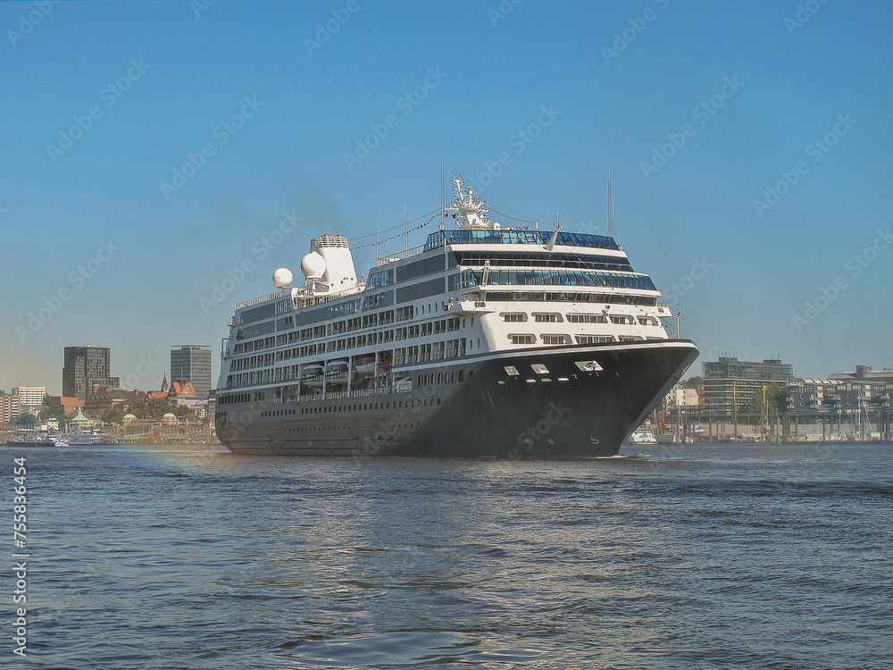 Luxury cruiseship cruise ship liner Quest on River Elbe towards Hamburg Hafen port in Germany with city skyline and landscape view