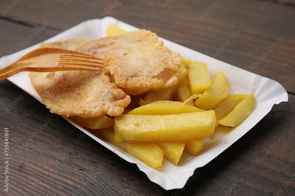 Delicious fish and chips served on wooden table, closeup