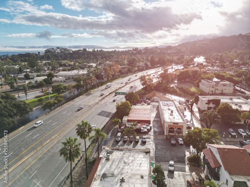 Aerial drone view over the 101 freeway Pacific Coast Highway as it passes through Santa Barbara, California on a bright late afternoon with sun flare.