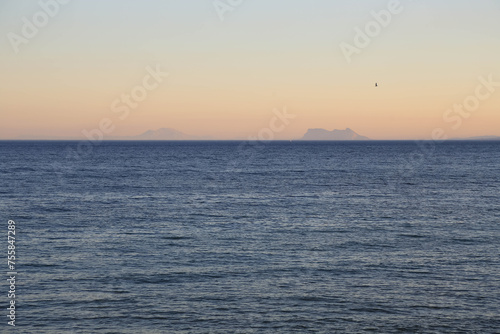 Evening seascape with peach-colored sunset sky and view of mount Gibraltar. Spain. Evening seascape with sunset sky overlooking Gibraltar. © Natalia