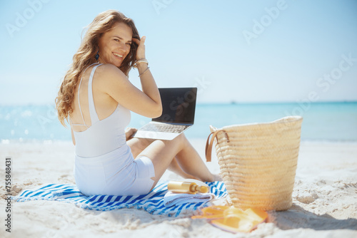 smiling stylish female on ocean shore with straw bag