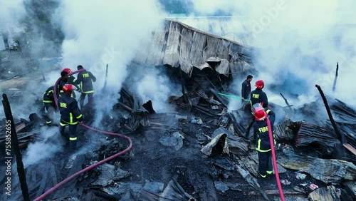 Firefighters bravely spray water on a massive fire in a rural market, using high-pressure hoses to extinguish the intense flames. Safety and disaster response are critical as they battle the blaze photo