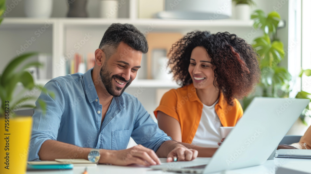 professional man and woman discussing work while looking at a laptop screen together in an office setting professional man and woman discussing work while looking at a laptop screen together in an office setting