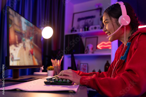 Host channel of young beautiful Asian gaming streamer, playing battle team gaming with multiplayer or single at warship on screen, wearing pastel color headset at digital neon light room. Stratagem. photo