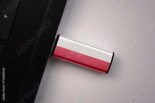 usb flash drive in notebook computer with the national flag of poland on gray background.