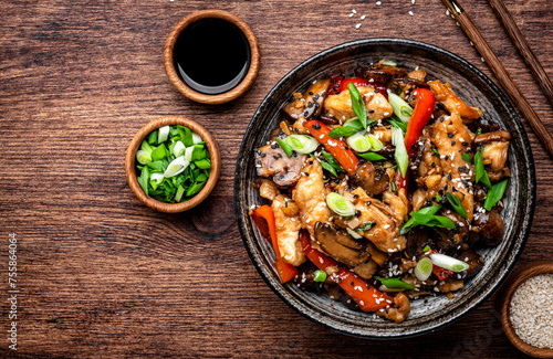 Stir fry turkey slices with red paprika, mushrooms, chives and sesame seeds with ginger, garlic and soy sauce. Old wooden table background, top view