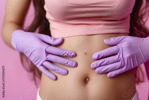 A dermatologist examining a young womans stomach adorned with purple gloves, focusing on moles and skin assessment. © Joaquin Corbalan