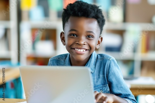 A talented small African American boy sitting in front of a laptop computer, focused on the screen.