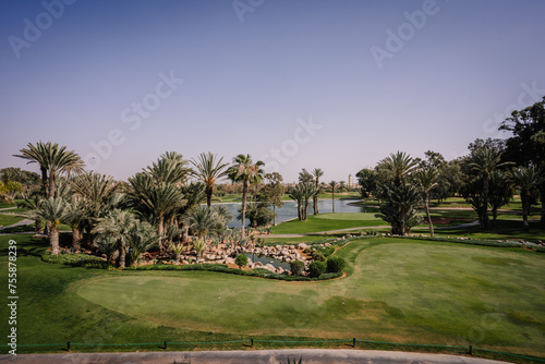 Agadir, Morocco - February 28, 2024- A scenic golf course with lush greenery, palm trees, a water feature, and clear skies.
