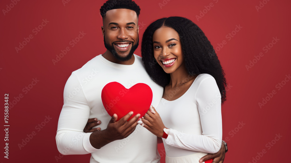 Smiling couple in white shirts, holding red heart-shaped objects, symbolizing love and togetherness.