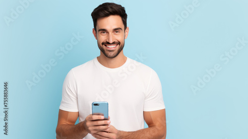 Young man smiling and holding his smartphone on a colored background © MP Studio