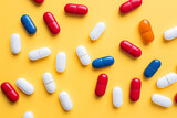 Colorful red, white, and blue capsules on a vibrant yellow background