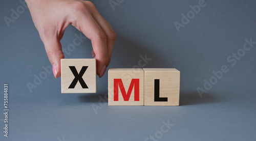 XML - Extensible Markup Language. Wooden cubes with word XML. Businessman hand. Beautiful grey background. Business and Extensible Markup Language concept. Copy space. photo
