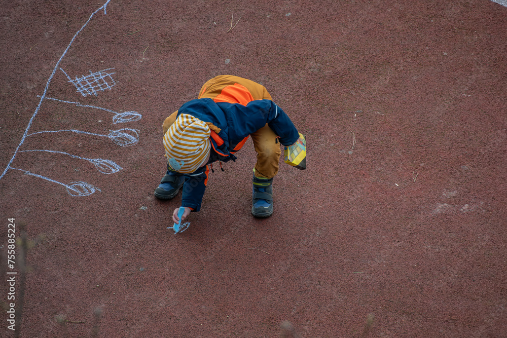 Kind spielt auf dem Spielplatz mit Kreide