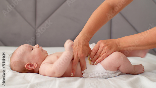 Mother changing the diaper of her newborn baby. Mother changes a diaper on her infant baby at home. Mom puts diapers on her newborn infant, on a changing table.